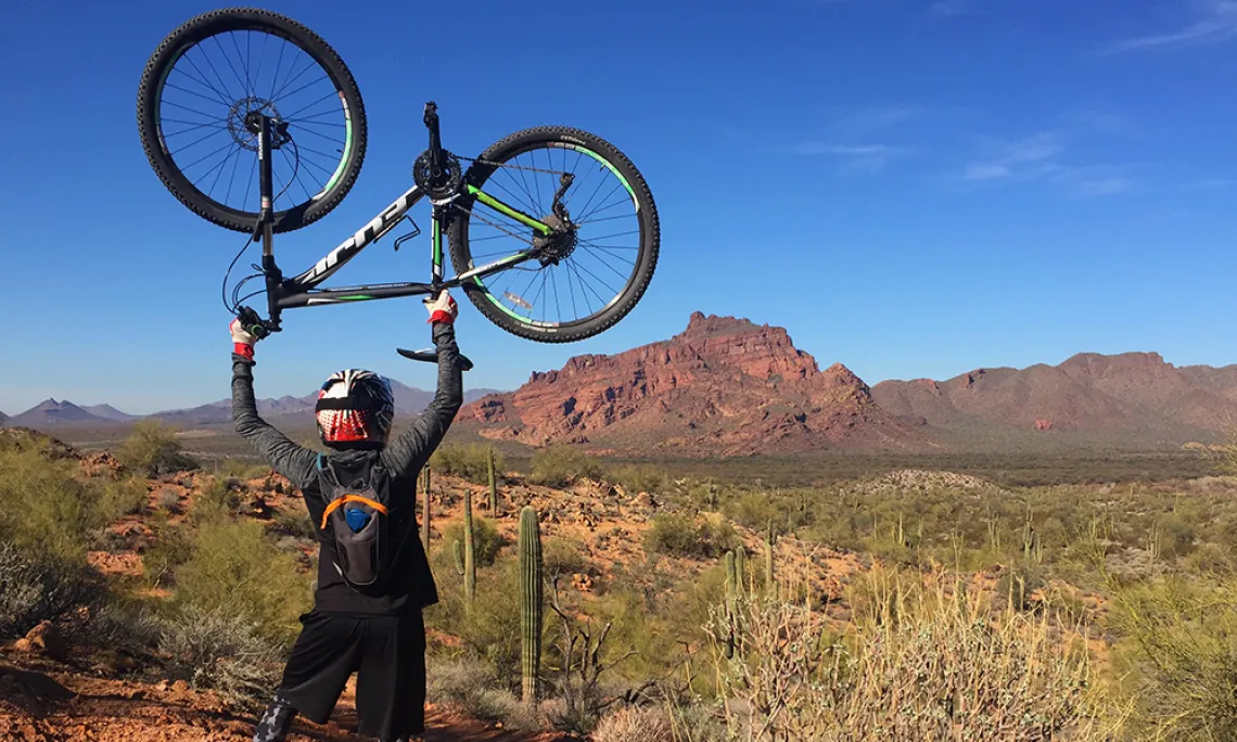 Man holding his bicycle above his head in Sedona, Arizona